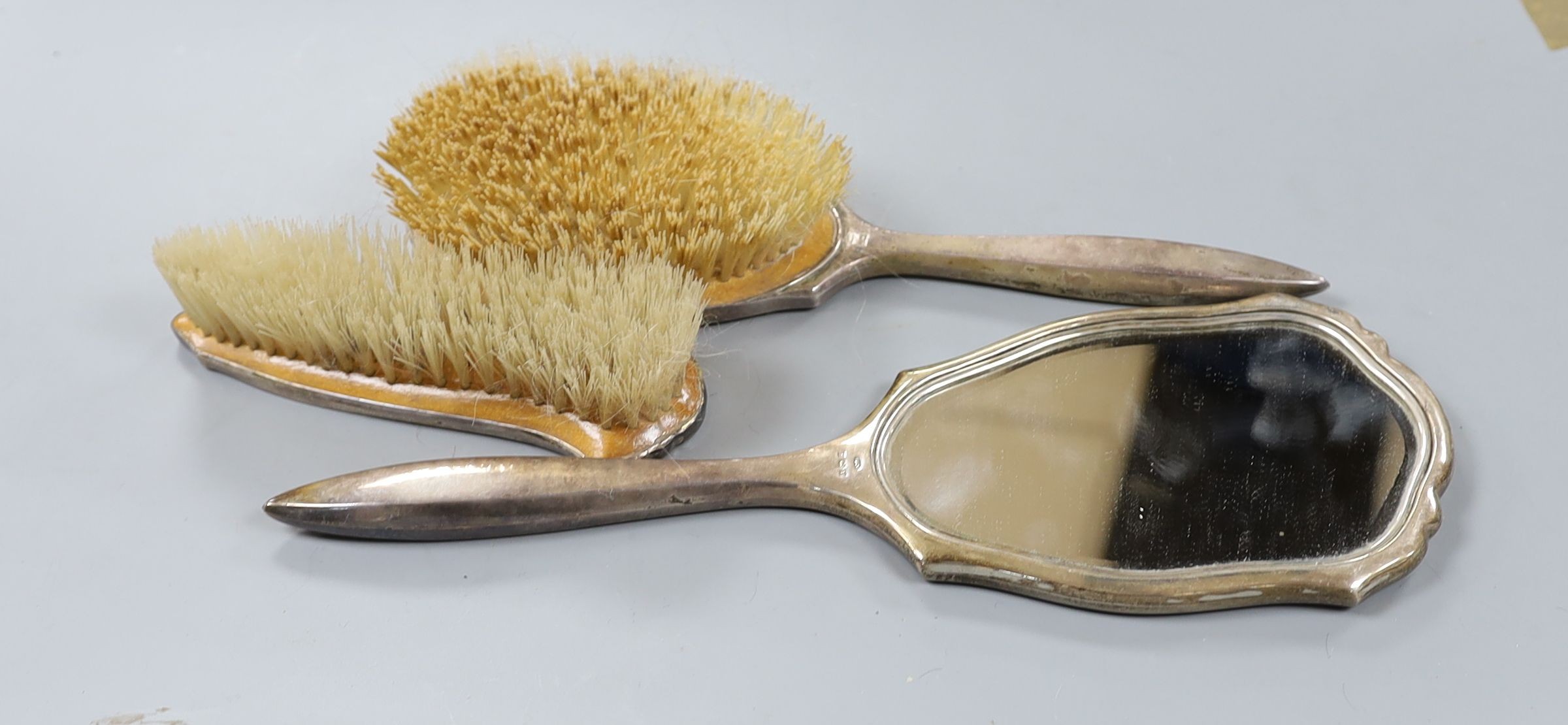 A silver three piece brush and mirror set.